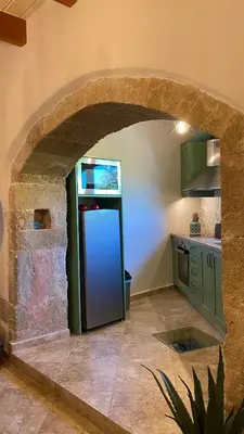 a kitchen with a stone archway with a refrigerator at Cellar - Shared Pool & Nature Views in Spiliá