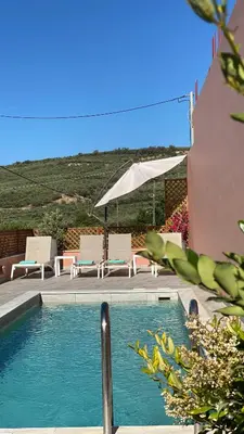 a swimming pool with two chairs and an umbrella at Cellar - Shared Pool & Nature Views in Spiliá