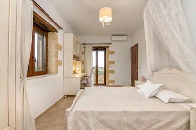 a bedroom with a white bed and a window at Villa Chrysseva in Plátanos