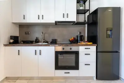 a kitchen with white cabinets and a black refrigerator at REN Apartment in Stalos