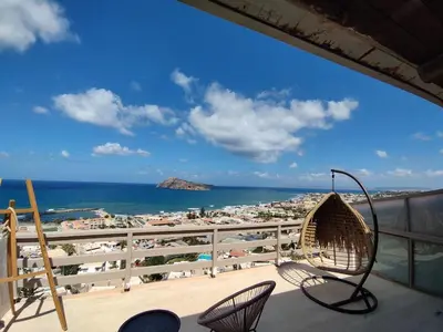 a balcony with a view of a beach and chairs at Meteoron Platanias in Plataniás