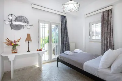 a bedroom with a bed and a table and windows at Esperado Gardens Maleme in Maleme