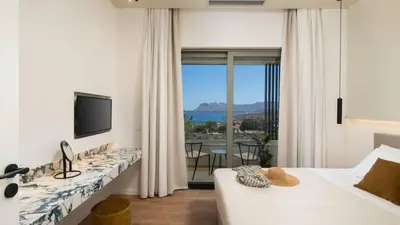a white room with a bed and a television and a couch at Two Seaview Villas With Elegant Design in Agios Onoufrios