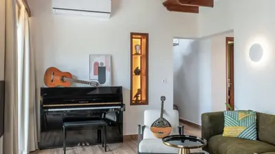 a living room with a piano and a chair at Two Seaview Villas With Elegant Design in Agios Onoufrios