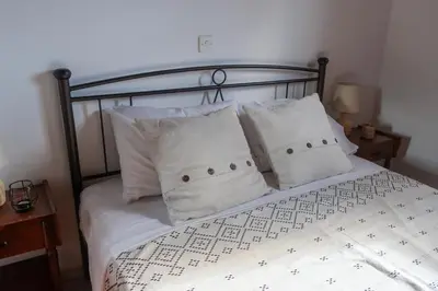 a bed with white sheets and pillows on it at Alkis Olive Grove Cottage in Vasilópoulon
