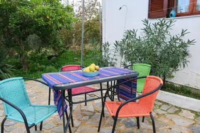 a table with chairs and a bowl of fruit on it at Alkis Olive Grove Cottage in Vasilópoulon