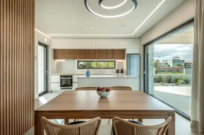 a kitchen and dining room with a wooden table and chairs at Deux Olives Luxury Villa in Maleme