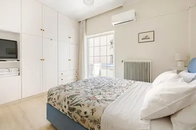 a white bedroom with a bed and a tv at Downtown house with seaview near to the beach in Chania Town