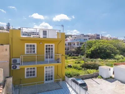 a yellow house with a balcony and a car at SeaREN Apartment in Stalos