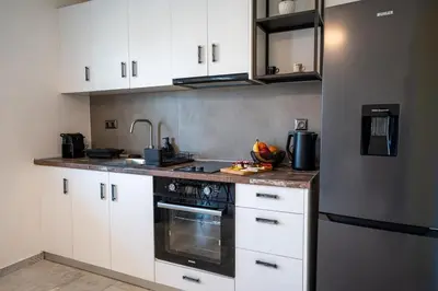 a kitchen with white cabinets and a stove top oven at SeaREN Apartment in Stalos