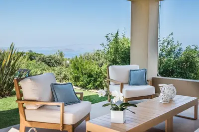 two chairs and a coffee table on a patio with a view at Villa Mariposa - panoramic sea view - near Chania city in Chania Town