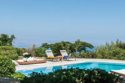 a villa with a swimming pool and two lounge chairs at Villa Mariposa - panoramic sea view - near Chania city in Chania Town