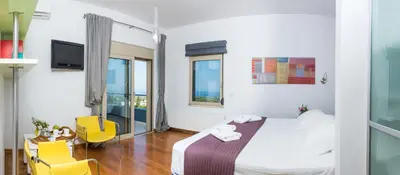 a hotel room with a bed and two yellow chairs at Villa Mariposa - panoramic sea view - near Chania city in Chania Town