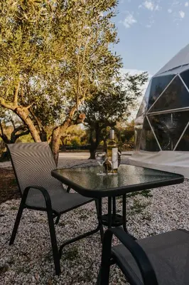 a table and a chair sitting next to a tent at Lemon Dome, Luxury Glamping Dome in Crete in Gavalochori
