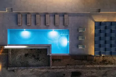 a large blue swimming pool with lights on a building at Villa Maninee-Bespoke Villa-Pool -BBQ-Seaview in Chania Town