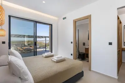 a bedroom with a bed with a view of the ocean at Villa Maninee-Bespoke Villa-Pool -BBQ-Seaview in Chania Town