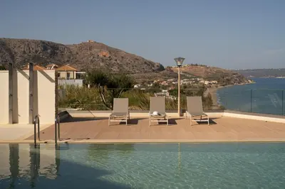 a swimming pool with chairs and a view of the water at Ocean Bay Sea View Apartment, Pool, Brand New, 2B in Kalyves