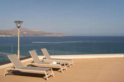 two lounge chairs and a light pole on a balcony at Ocean Bay Sea View Apartment, Pool, Brand New, 2B in Kalyves