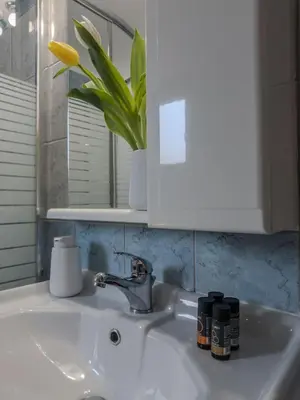a bathroom sink with a yellow flower in a mirror at Sunny Nest, Stylish & Bright Urban Retreat in Chania Town