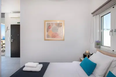 a white bedroom with a bed and a window at Stelios Florans Apartment in Chania Town