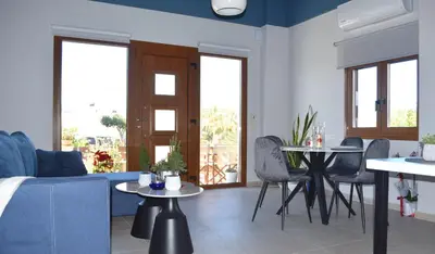a living room with a couch and a table and chairs at Modern Central Apartment - 400m to Beach in Kissamos