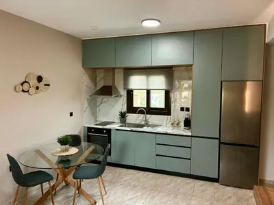 a kitchen with green cabinets and a table with chairs at Karadinos Apartment in Stílos