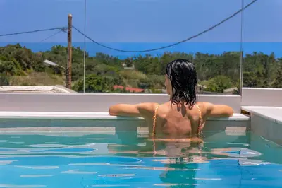 a woman sitting in the water in a swimming pool at Villa Metochi with Private Pool in Palio Gerani
