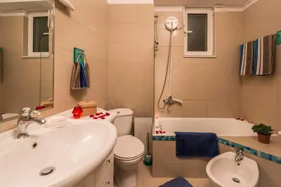 a bathroom with a sink and a toilet and a bath tub at Villa Joy Mare - Seaside Escape with Private Pool in Aghii Apostoli