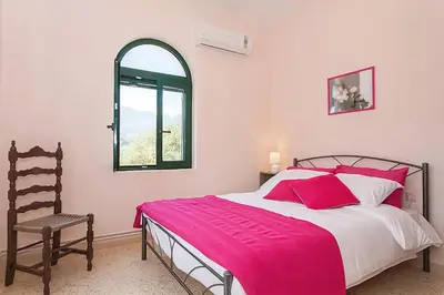 a bedroom with a bed and a chair and a window at 5-bedroom Country House in Crete - Olive Grove Retreat in Nerokhórion