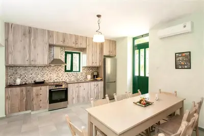 a kitchen with wooden cabinets and a table and chairs at 5-bedroom Country House in Crete - Olive Grove Retreat in Nerokhórion