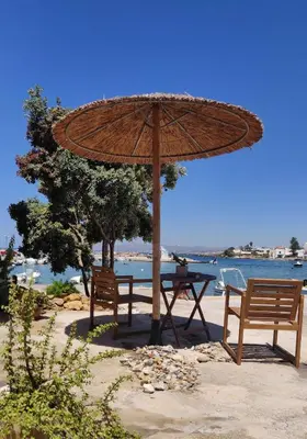 a table and two chairs under a umbrella on the beach at Vrahakia Apartment 1 in Marina Galatas in Galatás