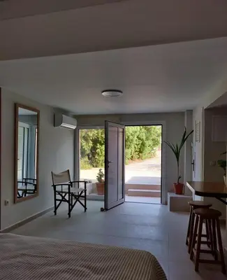 a bedroom with a bed and a table and a kitchen at Vrahakia Apartment 1 in Marina Galatas in Galatás