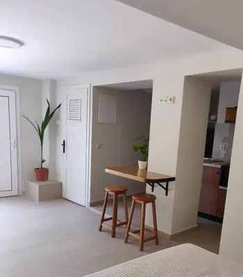 a dining room with a table and two stools at Vrahakia Apartment 1 in Marina Galatas in Galatás