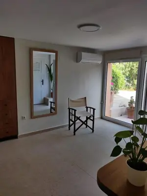 a living room with a chair and a mirror at Vrahakia Apartment 1 in Marina Galatas in Galatás