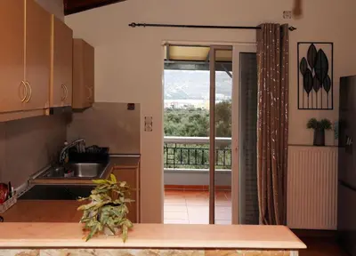 a kitchen with a door open to a balcony at Komvos Apartment in Souda
