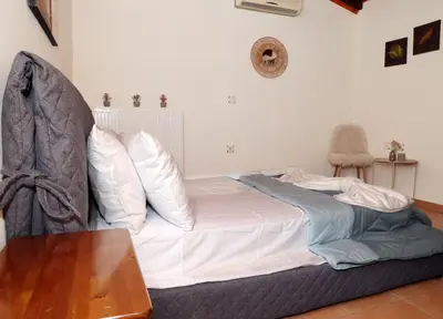 a bed with white sheets and pillows in a room at Komvos Apartment in Souda