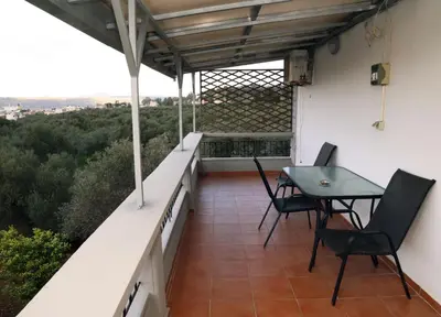 a patio with a table and chairs on a balcony at Komvos Apartment in Souda