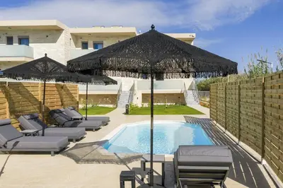a pool with chairs and umbrellas next to a building at Armdin Seaview Villa 1 in Módhion