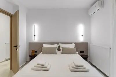 a white bedroom with a large white bed with three towels at Elan Stay in Chania Town