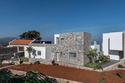 a large stone house with white buildings and palm trees at Aloni Villa with pool Kefalas in Vamos