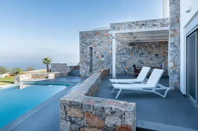a patio with two white chairs and a swimming pool at Aloni Villa with pool Kefalas in Vamos