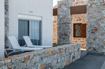two white chairs sitting on a stone wall at Aloni Villa with pool Kefalas in Vamos