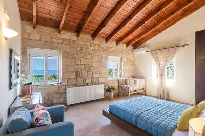 a bedroom with a blue bed and a stone wall at Villa Chara Chania in Agia Marina Nea Kydonias