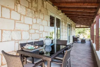 a patio with a table and chairs on a stone wall at Villa Chara Chania in Agia Marina Nea Kydonias