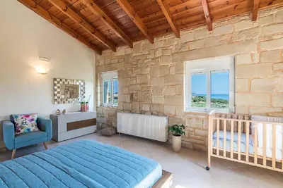 a bedroom with a blue bed and a stone wall at Villa Chara Chania in Agia Marina Nea Kydonias