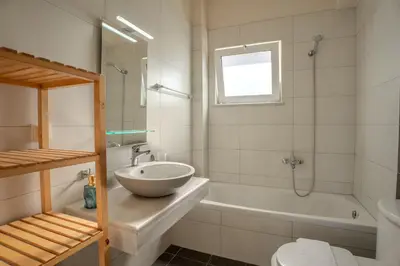 a bathroom with a sink and a tub and a toilet at Kalyves Sand- Beach front apartment in Kalyves
