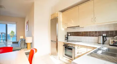 a kitchen with wooden cabinets and a red chair at Kalyves Sand- Beach front apartment in Kalyves