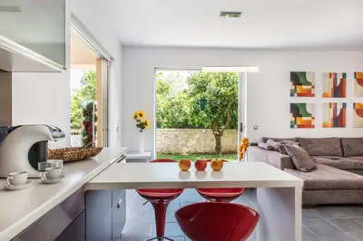 a kitchen and living room with a table and red stools at Villa Casa di Verde in Patellárion