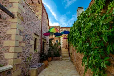 an alley with umbrellas hanging between two buildings at Aretaki villas in Astrátigos