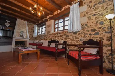 a living room with chairs and a table and a fireplace at Aretaki villas in Astrátigos
